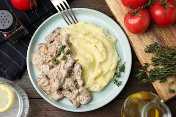 Delicious beef stroganoff with mashed potatoes and thyme served on wooden table, flat lay