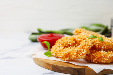 Deep fried squid rings, basil and ketchup on light marble table, closeup. Space for text