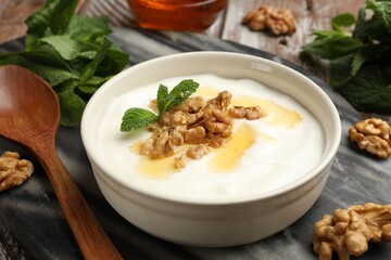 Delicious Greek yogurt with honey, nuts and mint on table, closeup