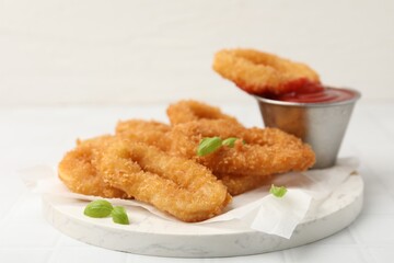 Deep fried squid rings with basil and ketchup on white tiled table, closeup. Space for text