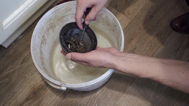 wash a dirty sink siphon in water, plumber in water cleans and washes clogged siphon in kitchen