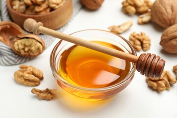 Sweet honey with walnuts and dipper on white table, closeup
