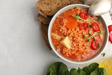 Delicious lentil soup with vegetables served on light grey table, flat lay. Space for text