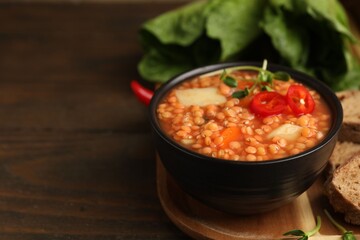 Delicious lentil soup with vegetables served on wooden table, closeup. Space for text