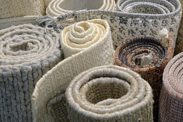 Group of assorted carpets and rugs of various sizes and colors, rolled