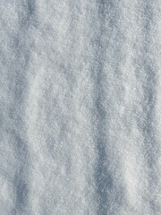 Fototapeta premium Close-up view of smooth snow surface with natural winter shadows.