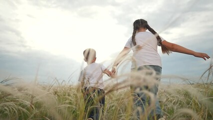 Children running in field holding hands together. Boy girl running across tall grass. Kid holding sibling tightly while running. Girl leads child care. Running children holding hands in sunny field. - Powered by Adobe