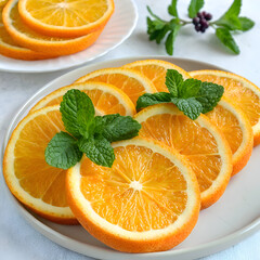 Close up of orange slices on a plate garnished with mint leaves and a sprig of green leaves