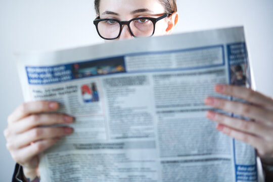 Close-up of young woman reading newspaper.