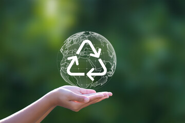 Hand with recycle logo on natural green background. Earth Day concept.
