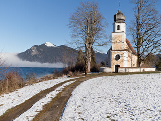 Kirchlein auf der Halbinsel des bayerischen Walchensees mit dem Jochberg und Nebeleinfall im Hintergrund