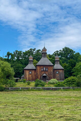 Green summer colors light up the countryside among old wooden houses and ancient churches in Ukraine, creating a warm nostalgic atmosphere.
