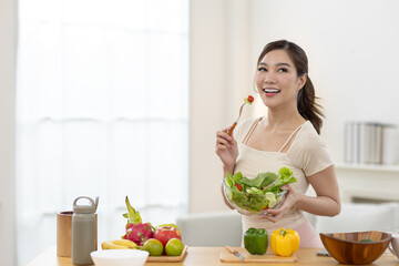 Smiling young Asian women enjoying fresh vegetable salad in kitchen, promoting clean eating, wellness lifestyle, healthy food choices, daily nutrition habits with positive energy. © Ratirat