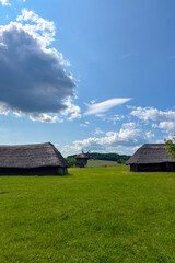Green summer colors light up the countryside among old wooden houses and ancient churches in Ukraine, creating a warm nostalgic atmosphere.
