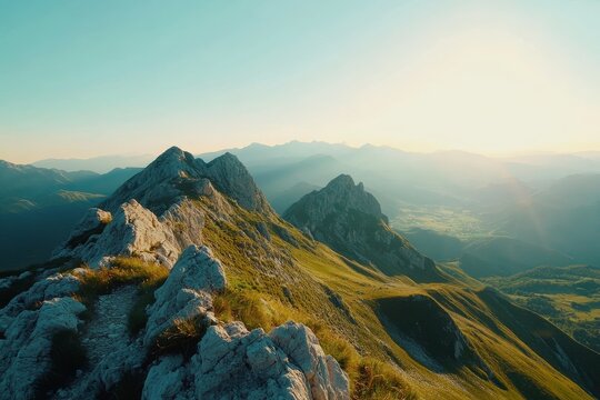 Narrow path along rugged mountain crest overlooking vast green valleys and peaks