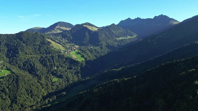 Drone aerial flight over forests above Montreux with a distant view of the Dent de Jaman peak in the Swiss Alps on a clear day
