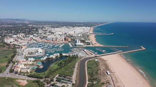 Vilamoura aerial view aerial coastal view vilamoura resort and marina stretch with long sandy coastline, protective jetties, blue ocean, resort buildings and winding waterfront roads