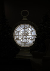 A steampunk-style pocket watch clock with Roman numerals and festive silhouettes of Santa’s sleigh, flanked by Christmas trees, glowing warmly in a cozy indoor holiday setting with vintage charm.