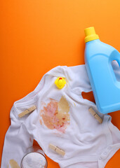 Vertical photo format.A Stained Baby Shirt, Resting with Detergent on a Bright Background Surface