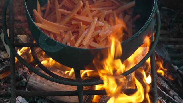 Carrots cooking, cast iron pot, open campfire, delicious outdoor food preparation
