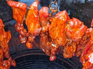 Cose-up overhead shot of multiple pieces of brightly glazed, reddish-orange roasted barbecue pork...