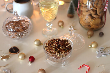 Cookie jar, tea, wine, nuts, books, lit candles and Christmas decorations on the table. Cozy Christmas hygge at home. Selective focus.
