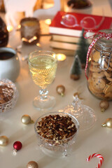 Cookie jar, tea, wine, nuts, books, lit candles and Christmas decorations on the table. Cozy Christmas hygge at home. Selective focus.