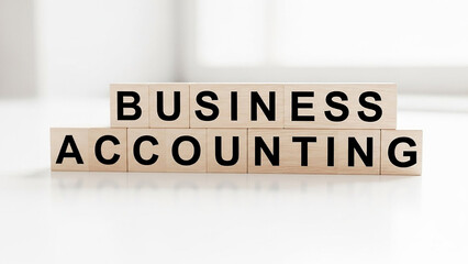 Business accounting text on wooden blocks stacked on a white surface in a well lit environment