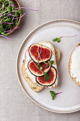 Slices of white bread with young cream cheese, freshly sliced figs and radish sprouts.