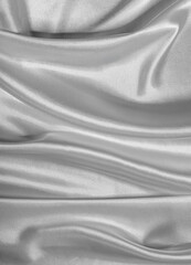 Silky, smooth gray satin fabric drapes with flowing folds and a reflective sheen, creating an elegant textile background.
