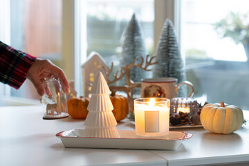 Candle light with Christmas decoration atmosphere while hand putting ornament to decorate on table.