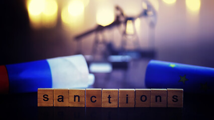 word sanctions spelled in letters on table made of wooden block letters with dramatic lighting and...