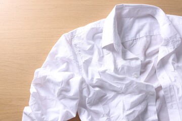 White creased shirt on wooden table, top view