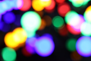 Fototapeta premium Blurred view of bright Christmas lights on dark background, bokeh effect