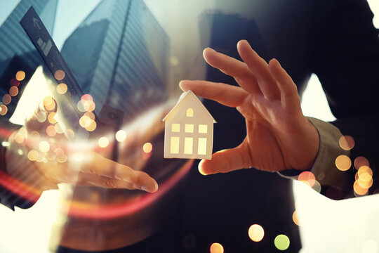 Real estate agent holding a toy house. Close up of businessman hand. Smart home, ai and information concept. Double exposure