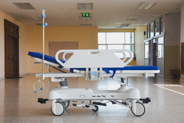 A medical gurney with an IV pole in a bright hospital corridor.