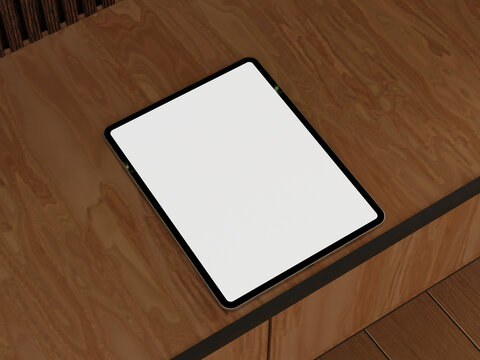 Tablet mockup with empty screen on a wooden floor near books in a modern workspace.