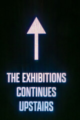 Stockholm, Sweden  A sign and an arow on a wall says the Exhibitions Continues Upstairs.