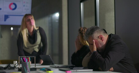 Female boss publicly scolding male employee during tense office meeting, man hides face in shame as colleagues look on, highlighting workplace conflict and humiliation