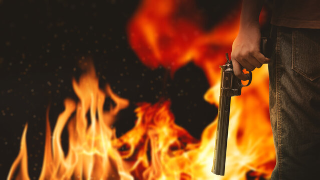 Human hand holding a revolver handgun in front of a fiery background. Concept of gun violence