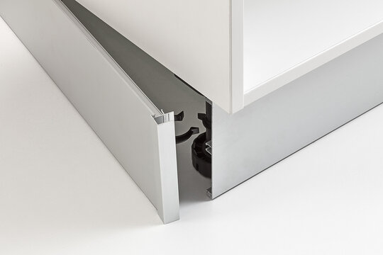 Close-up of kitchen cabinet base showing the locking clip mechanism for securing the kickboard panel.