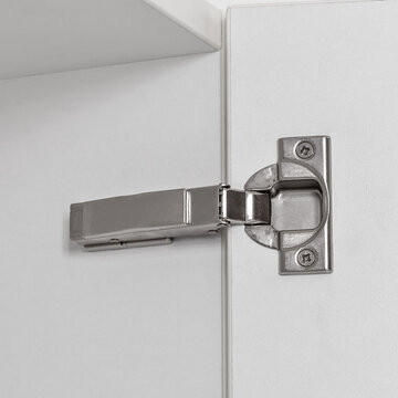 Close-up of concealed hinge mounted on a kitchen wall cabinet door, showing precise and adjustable opening mechanism.