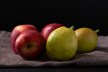 Red apple and pear fruit on fabric with black background