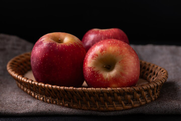 Red apple fruit in basket on fabric with black background