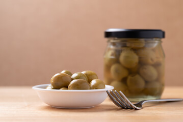 Pickled olives, Pitted green olives in a bowl and glass jar on wooden background