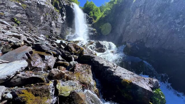 Dombai-Ulgen Gorge, Chuchhur waterfall is framed by malachite greenery of grasses and dense forests. A waterfall flowing down from a glacier. A two-stage stream with white foam, near the Chuchhur pass