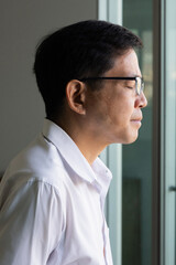 Side portrait of relaxed Asian man with vitiligo, an uneven skin color condition. The man closing his eyes in contemplating mood, indoor scene.