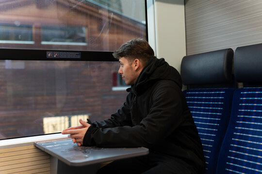 Young man riding a train looking out window
