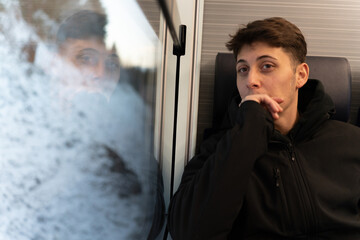 Young man traveling by train looking thoughtful
