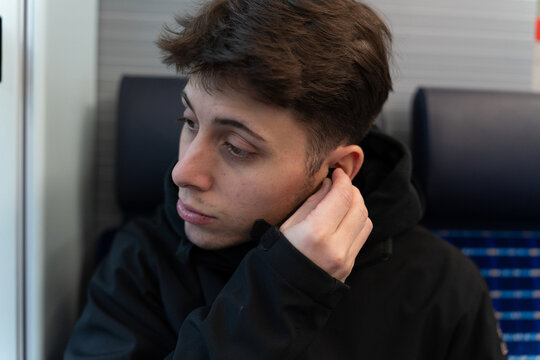 Young man traveling by train listening to music - Powered by Adobe